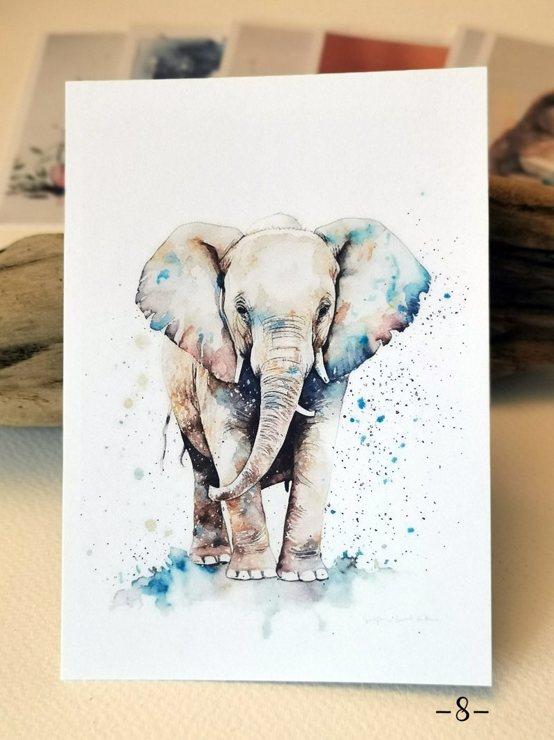 Pu&ograve; includere: Dipinto ad acquerello di un cucciolo di elefante in piedi su uno sfondo di schizzi blu e bianco. L'elefante &egrave; di colore marrone chiaro con una proboscide e orecchie di colore grigio chiaro.