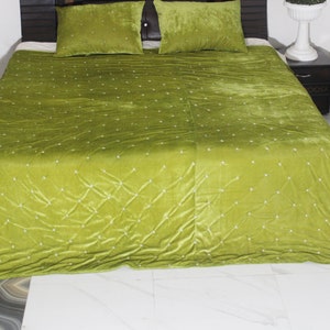 May include: A bed dressed with a lime green velvet quilt and two matching pillowcases. The quilt features a diamond pattern with small white accents. The bed is against a dark brown headboard.
