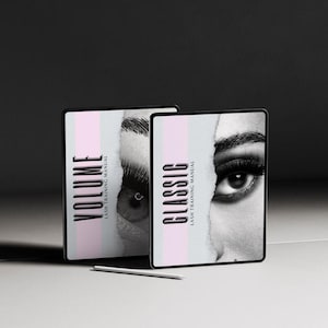 May include: Two black tablets with the words "VOLUME LASH TRAINING MANUAL" and "CLASSIC LASH TRAINING MANUAL" in white. Each tablet features a black and white close-up of an eye. A white stylus rests in front of the tablets.