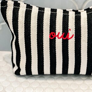 black and white striped cosmetic bag with red oui writing