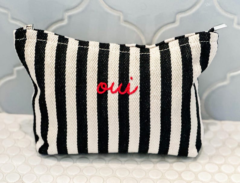 black and white striped cosmetic bag with red oui writing