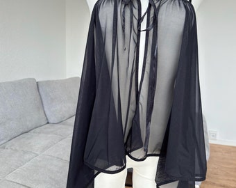 May include: Black sheer top with a tie at the front and thin straps. The top is on a white mannequin with a black choker.