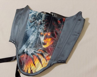 May include: A gray corset with a black and red print of a demonic figure with flames. The corset has a lace-up back and is made of a satin-like material.