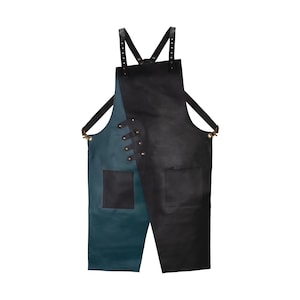 Könnte beinhalten: Zweifarbiges Kochschürze in Schwarz und Teal. Es hat eine große Tasche auf jeder Seite und verstellbare Lederriemen. Die Schürze wird mit Nieten und Lederriemen befestigt.