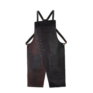 Könnte beinhalten: Zweifarbiges Leder-Schürze in Schwarz und Braun. Mit verstellbaren Trägern, zwei Vordertaschen und Messingnieten. Das Design umfasst eine asymmetrische Front. Geeignet für Handwerker oder Köche.