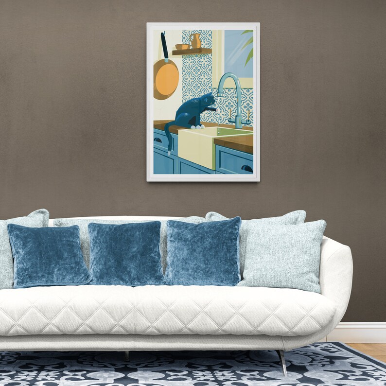 Living room with a poster on the wall. The illustration on the art print shows a black cat in a kitchen with azulejo tiles as can often be found in Spain and Portugal. The artwork gives a Mediterranean feel. The cat is playing with dripping water.