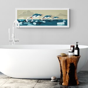 Long horizontal poster or art print hanging in a bathroom with artwork of three gentoo penguins that are making speed between the ice floes in the ocean around Antarctica. The panorama has shades of beige, white and blue colors.