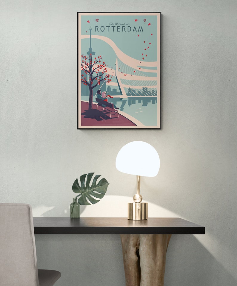 Home office with a poster or art print of an illustration of the city of Rotterdam in the Netherlands. It is a romantic scene of a couple sitting on a bench overlooking the river. Leaves drawn as hearts are flying through the sky.