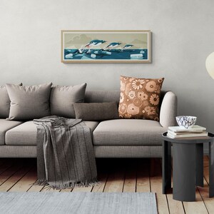 Long narrow horizontal poster or art print hanging in a living room with artwork of three gentoo penguins that are making speed between the ice floes in the ocean around Antarctica. The panorama has shades of beige, white and blue colors.