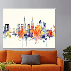 K&ouml;nnte beinhalten: Ein gro&szlig;er Leinwanddruck mit einer farbenfrohen Aquarellmalerei der Skyline von New York City. Das Kunstwerk zeigt ber&uuml;hmte Geb&auml;ude und Br&uuml;cken in Orange-, Blau- und Lilat&ouml;nen vor einem wei&szlig;en Hintergrund. Der Druck befindet sich &uuml;ber einem orangefarbenen Sofa.