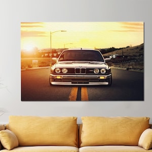 Könnte beinhalten: Ein silberner BMW E30 fährt auf einer Straße mit Sonnenuntergang im Hintergrund.