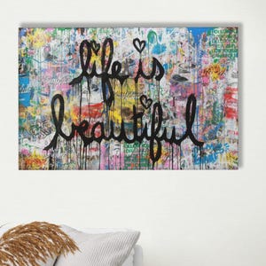 Puede incluir: Una obra de arte abstracta y colorida con la frase "life is beautiful" en escritura negra. El fondo es un collage de estilo grafiti con varios colores y patrones, incluyendo salpicaduras de rojo, azul y amarillo.