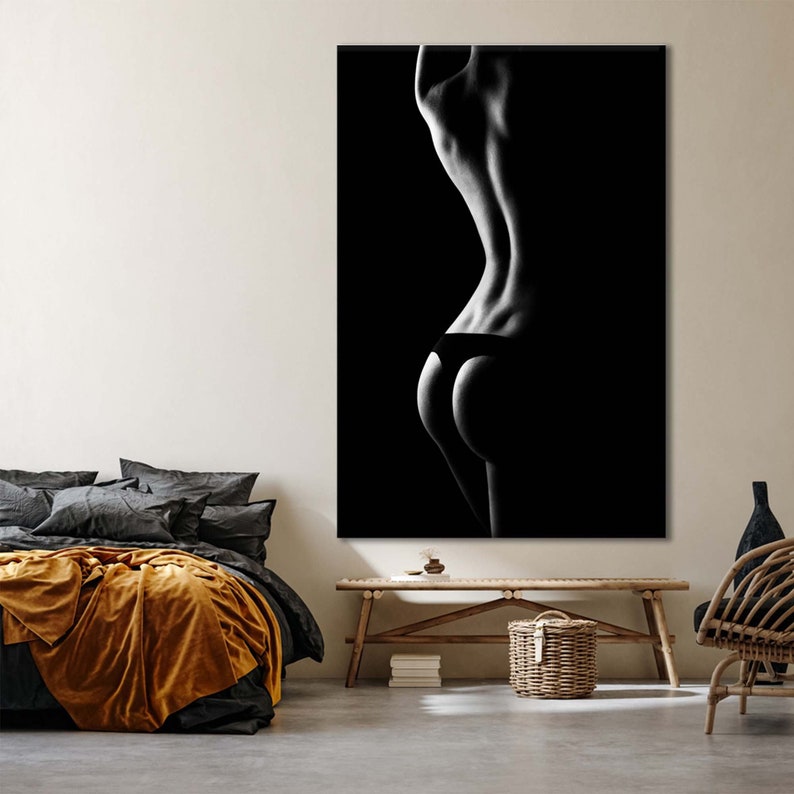 May include: A black and white photograph of a person's back and hips, with the person wearing black underwear. The image is in a dark, shadowy style.