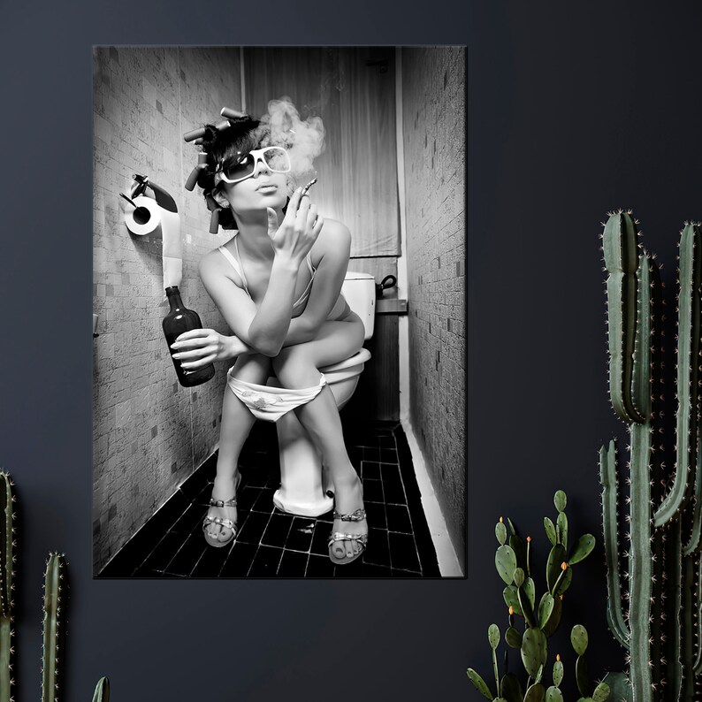 May include: Black and white photograph of a person sitting on a toilet, smoking a cigarette, and holding a bottle. The person is wearing sunglasses, curlers, and lingerie. The background is a tiled bathroom.