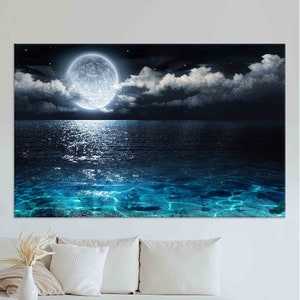 May include: A full moon shines brightly over a dark blue ocean with white clouds in the sky. The moon's reflection is visible in the water.