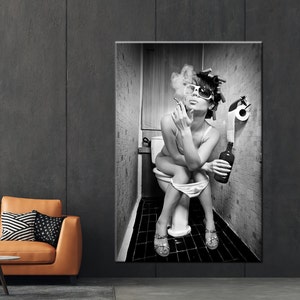 May include: Black and white wall art print of a person sitting on a toilet, smoking a cigarette, and holding a bottle. The person is wearing sunglasses and hair rollers. The bathroom has a roll of toilet paper.
