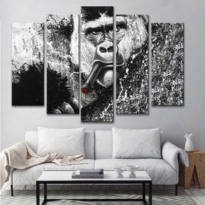 May include: Black and white canvas wall art featuring a gorilla smoking a cigar. The gorilla's face is in the center of the image, with a black and white splatter background.