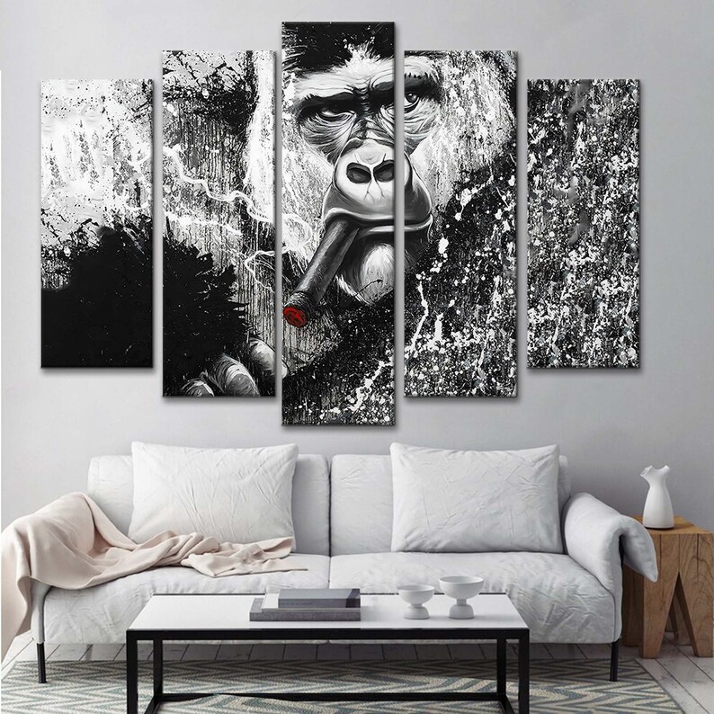 May include: Black and white canvas wall art featuring a gorilla smoking a cigar. The gorilla's face is in the center of the image, with a black and white splatter background.