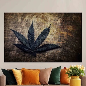 Puede incluir: Una hoja de cannabis verde oscuro sobre un fondo de madera desgastado. La hoja est&aacute; enfocada, mientras que el fondo est&aacute; desenfocado.