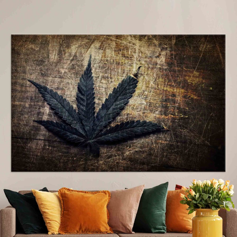 Puede incluir: Una hoja de cannabis verde oscuro sobre un fondo de madera desgastado. La hoja est&aacute; enfocada, mientras que el fondo est&aacute; desenfocado.