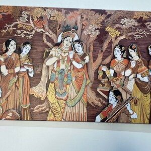 May include: A colorful painting depicting a scene from Hindu mythology. The central figures are Krishna and Radha, surrounded by other figures. The painting is done in a traditional style with intricate details and vibrant colors.