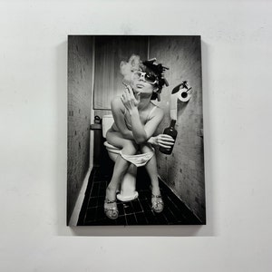 May include: Black and white photograph of a person sitting on a toilet, smoking a cigarette, and holding a bottle. The person is wearing sunglasses, curlers, and sandals. A roll of toilet paper is visible.