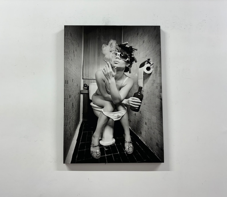 May include: Black and white photograph of a person sitting on a toilet, smoking a cigarette, and holding a bottle. The person is wearing sunglasses, curlers, and sandals. A roll of toilet paper is visible.