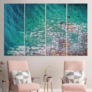 Op de afbeelding: Een driedelig canvasprint met een abstract ontwerp in turquoise en bruine kleuren. Het ontwerp lijkt op een gebarsten, getextureerd oppervlak met een vleugje water.