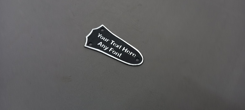 Puede incluir: Golpeador de guitarra negro con texto blanco que dice "Your Text Here Any Foil".