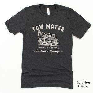Pu&ograve; includere: T-shirt grigio scuro m&eacute;lange con grafica bianca di un carro attrezzi e la scritta "TOW MATER TOWING & SALVAGE RADIATOR SPRINGS". La maglietta &egrave; girocollo e ha maniche corte.