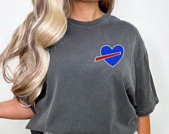 May include: Dark grey t-shirt with a blue heart and red stripe design. The shirt has short sleeves and a crew neck. The word "Pepper" is printed on the top right of the image.