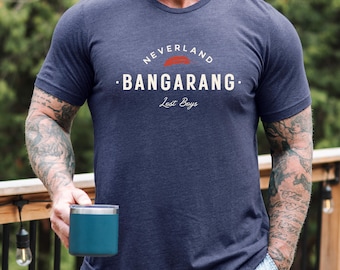 May include: A heather navy blue short-sleeve t-shirt featuring the text NEVERLAND BANGARANG and Lost Boys in white, with a red brushstroke graphic above the word BANGARANG. The shirt has a crew neckline and a heathered fabric texture.