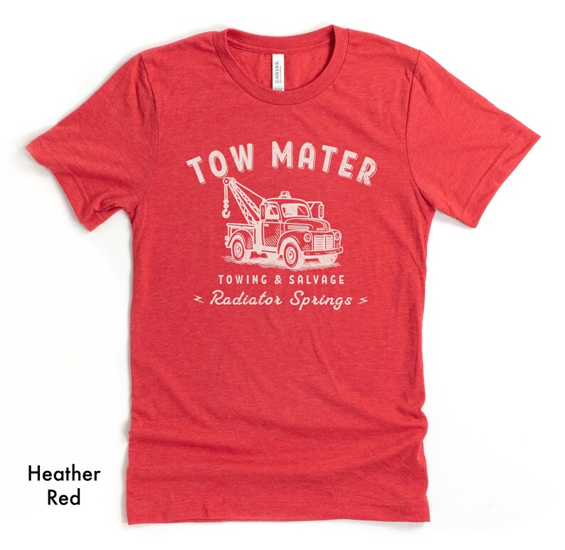 Pu&ograve; includere: T-shirt rosso melange con grafica bianca di un carro attrezzi e le parole "TOW MATER" sopra. Sotto il camion le parole "TOWING & SALVAGE" e "Radiator Springs". La maglietta &egrave; in materiale morbido.