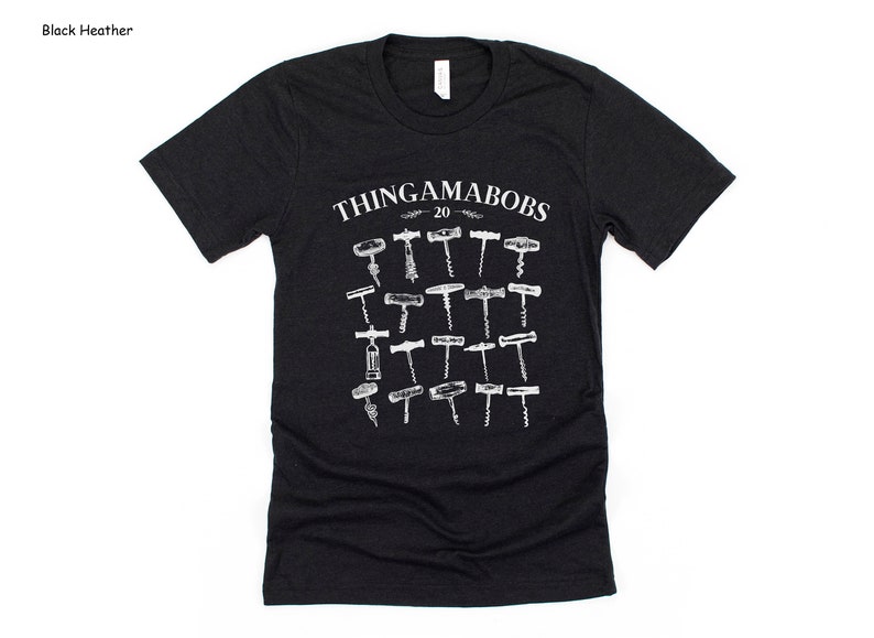 May include: A black heather grey t-shirt with a white graphic of the text "Thingamabobs 20" and a collection of 20 different vintage corkscrews.