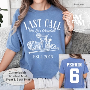 May include: Blue jean colored t-shirt with the text "LAST CALL For Jr's Baseball" and a graphic of a baseball glove, cocktails, and a baseball. The back of the shirt has the name "PERRIN" and the number "6".