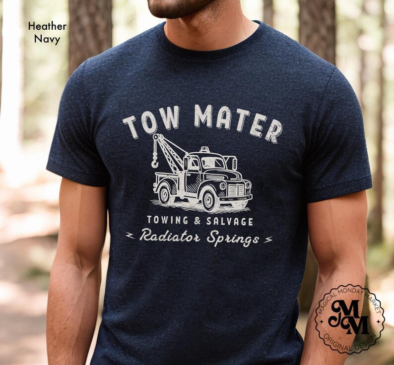 Pu&ograve; includere: T-shirt blu navy con grafica bianca di un carro attrezzi e la scritta "TOW MATER TOWING & SALVAGE Radiator Springs". La maglietta ha girocollo e maniche corte. Il design &egrave; in stile vintage.