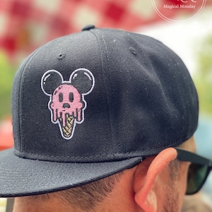 May include: Black baseball cap with a pink and white ice cream cone Mickey Mouse design.