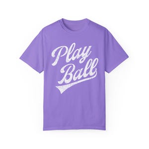 K&ouml;nnte beinhalten: Ein lila T-Shirt mit einer wei&szlig;en Grafik im Vintage-Stil, auf dem "Play Ball" mit einem Baseball-Swoosh steht.