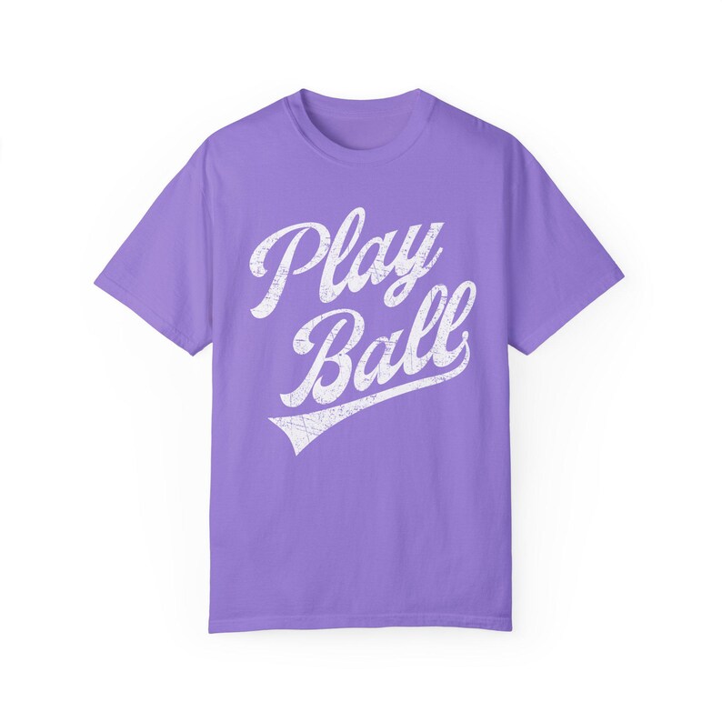 K&ouml;nnte beinhalten: Ein lila T-Shirt mit einer wei&szlig;en Grafik im Vintage-Stil, auf dem "Play Ball" mit einem Baseball-Swoosh steht.