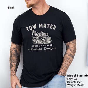 Pu&ograve; includere: T-shirt nero taglia XL con grafica di un carro attrezzi e la scritta "TOW MATER" sopra, con "TOWING & SALVAGE" e "Radiator Springs" sotto. La maglietta &egrave; realizzata in materiale morbido.