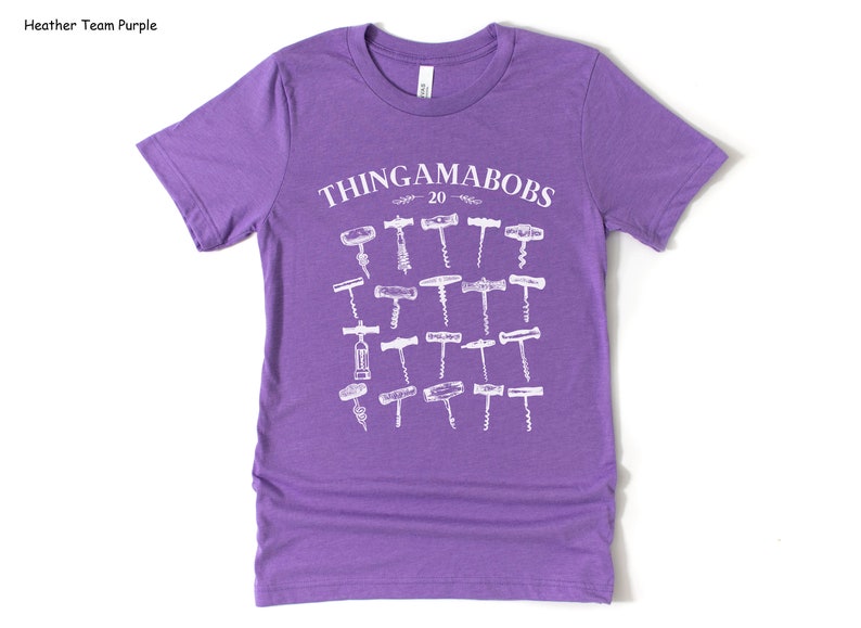 May include: Purple short-sleeved t-shirt with a white graphic of the text "THINGAMABOBS 20" and a collection of 20 different vintage corkscrews.
