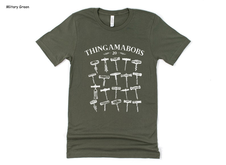 May include: A military green t-shirt with a white graphic of the text "Thingamabobs - 20" and a collection of 20 different types of corkscrews.