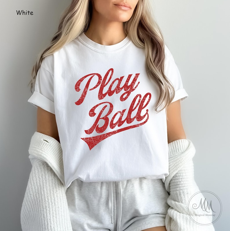 K&ouml;nnte beinhalten: Wei&szlig;es T-Shirt mit rotem Vintage-Text, der "Play Ball" sagt.