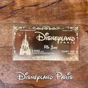 Puede incluir: Un boleto dorado de Disneyland Par&iacute;s con el texto "YOUTH ADMISSION TICKET", "January 2-4, 2023", "DISNEYLAND PARIS", "RID JANE", "$ FREE AGES", "Enchanted Christmas Experience", "ADMIT ONE" y "16074505". El boleto presenta una silueta del castillo de la Bella Durmiente.