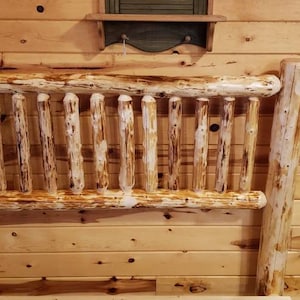 May include: A rustic wooden headboard with a whitewashed finish. The headboard is made of natural wood with knots and imperfections, giving it a unique and charming look.