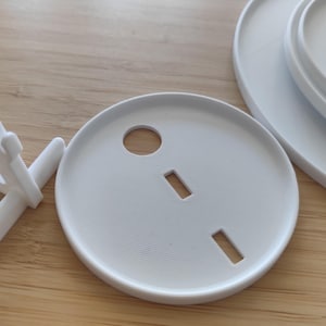 May include: A white plastic display stand with a triangular support structure and a set of three circular white plastic plates. Each plate features a central circular cutout and two rectangular slots, designed for assembly with the display stand.