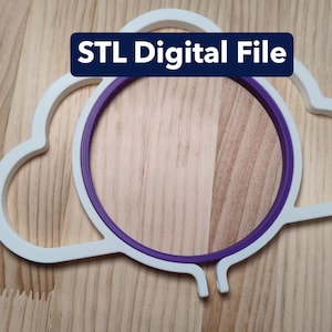 Puede incluir: Un marco blanco con forma de nube y un anillo interior circular de color morado. Una etiqueta rectangular azul oscuro con texto blanco dice STL Digital File. El objeto está hecho de material rígido y tiene una abertura central.