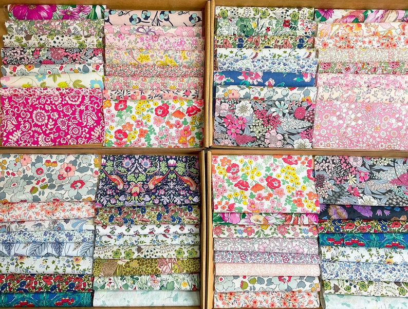 May include: A selection of floral fabric swatches displayed in wooden boxes. The fabrics showcase a variety of colourful floral patterns in pink, red, blue, and green. The swatches are neatly arranged, displaying a range of designs and colours.
