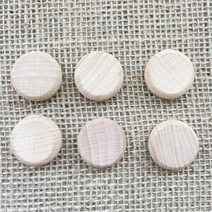 K&ouml;nnte beinhalten: Sechs runde Holzscheiben, jede mit einer glatten, hellbraunen Oberfl&auml;che. Die Scheiben sind in zwei Reihen zu je drei auf einem gewebten Jute-Hintergrund angeordnet.