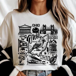 May include: White sweatshirt with a black and white graphic design featuring an outline of the state of Ohio with various landmarks and the text "Ohio, Buckeye State".